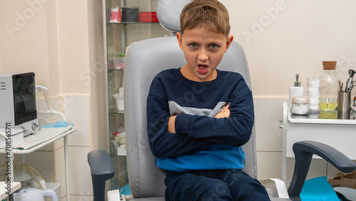 a little boy, a fair-haired teenager, sits in the otolaryngologist's office, waiting for an examination, worried, but smiling. Place for inscription photo