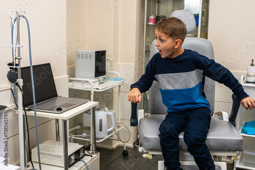 a little boy, a fair-haired teenager, sits in the otolaryngologist's office, waiting for an examination, worried, but smiling. Place for inscription