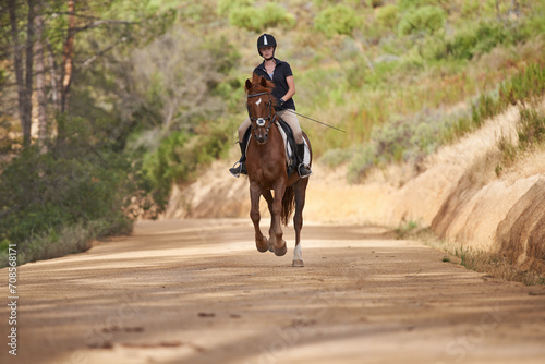 Equestrian, trail and riding a horse in nature on adventure and journey in countryside. Ranch, animal and rider outdoor with pet on path in forest or woods for hobby on farm with girl in summer © Tasneem H/peopleimages.com