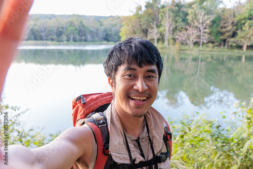 Happy Asian traveller man takes a selfie photo on a lake at the mountain.