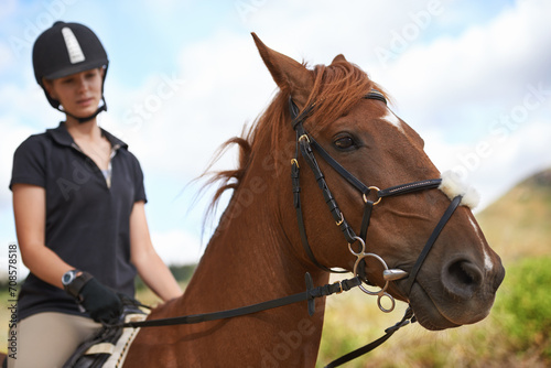 Equestrian, horse and woman riding in nature on adventure and journey in countryside. Ranch, animal and rider outdoor with hobby, sport or travel with pet on farm trail or girl in summer on blue sky © Tasneem H/peopleimages.com