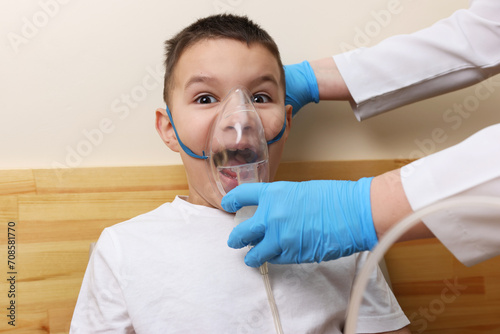 The boy is preparing for the nebulizer inhalation procedure.