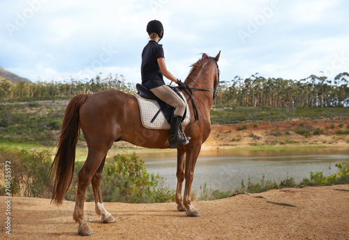 Equestrian, woman and horse in nature for ride on adventure and journey in countryside. Ranch, animal and rider outdoor with hobby, sport or pet on farm trail with girl in summer at river with peace © Tasneem H/peopleimages.com