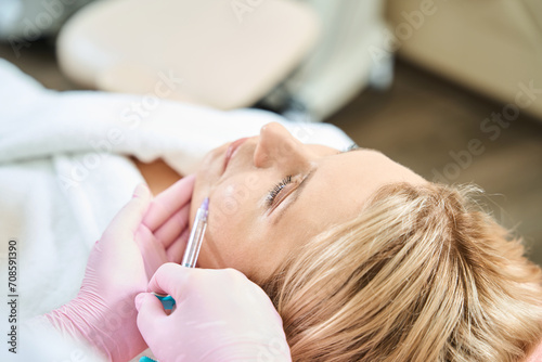 Partial female beautician doing face beauty injection of woman in beauty salon