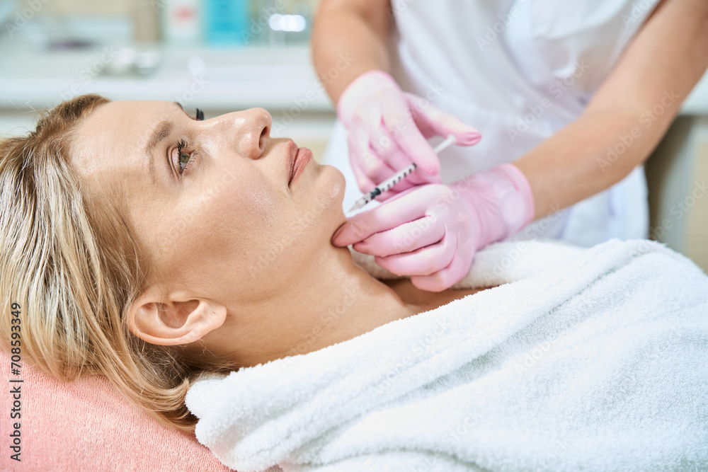 Side view of cosmetologist doing face beauty injection with syringe of woman