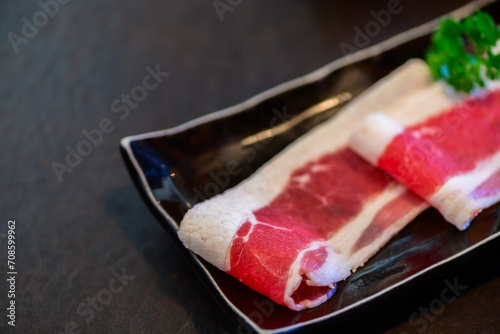 Sliced wagyu marbled beef for yakiniku on plate on black background,