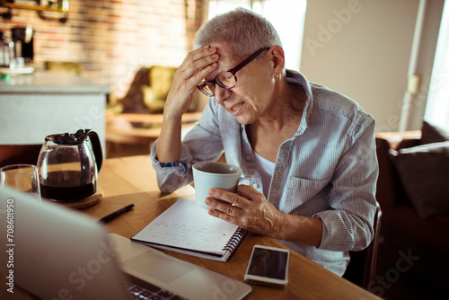 Senior woman having headache while working from home © Vorda Berge