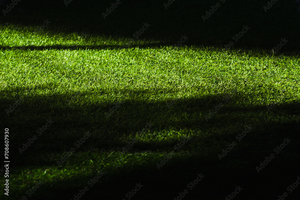 Green artificial turf in shade of sunlight.