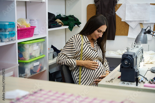 Photos Pregnant craftswoman in the workshop works at a sewing machine