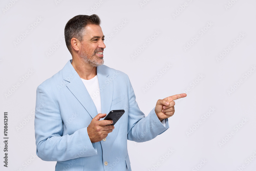 Happy older middle aged professional business man wearing suit holding mobile cell phone using online banking app on smartphone pointing aside at copy space standing isolated on white background. Happy older middle aged professional business man wearing suit holding mobile cell phone using online banking app on smartphone pointing aside at copy space standing isolated on white background.