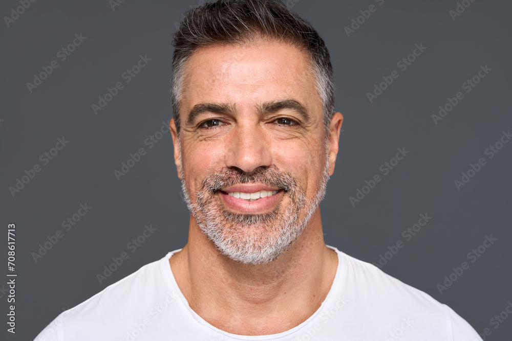 Happy confident handsome healthy mature older man, smiling middle aged male model wearing white t-shirt standing isolated on gray background advertising skin care and dental smile concept. - obrazy, fototapety, plakaty 