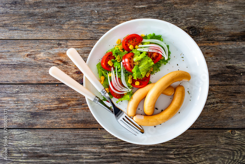 Breakfast - boiled sausages and fresh vegetables served on wooden table photo