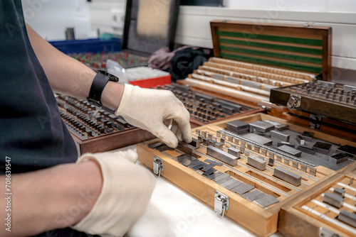 The worker selects gauge blocks to obtain the required control size of the part being manufactured and adjusts the measuring tool of a CNC metal-cutting machine.