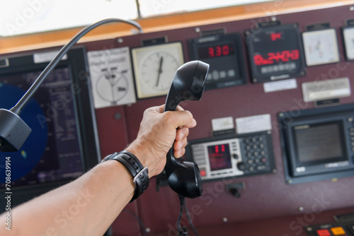 Navigational control panel and VHF radio with hand. Radio communication at sea. Working on the ship's bridge. photo