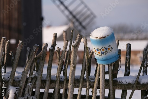Pot painted with traditional patterns on wooden fence next to historic wooden windmill in the village of Mokry Dwor in Zulawy Gdansk photo