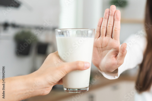 Allergy asian young woman, girl hand in deny, no or push out to avoid for drink milk at home, unhappy and bad stomach ache. Lactose intolerance and dairy food, health problem, belly suffer concept. photo
