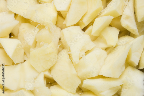 A close-up of freshly cut raw potatoes with small bubbles, soaking ready for cooking. Food preparation.