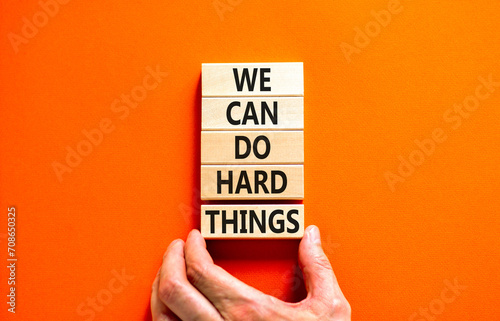 We can do hard things symbol. Concept words We can do hard things on wooden blocks. Beautiful orange table orange background. Businessman hand. Business, we can do hard things concept. Copy space. photo