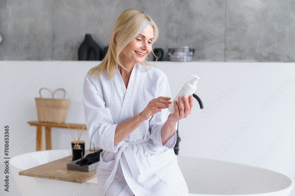 Mature woman hold moisturizer and reading composition of cosmetic product Mature woman hold moisturizer and reading composition of cosmetic product