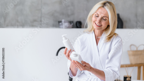 Mature woman wearing bathrobe choosing product for morning routine