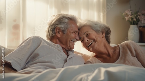 Senior bliss at home: A happy senior couple shares laughter in bed, showcasing the joy and emotional connection of their retirement.