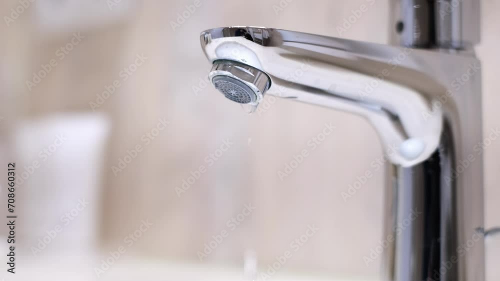 Drop of water drips from the tap. Beautiful fresh and clean water flowing from a tap. Close-up slow motion broken chrome faucet in the bathroom. Everyday problems, wasting water and energy. Drop of water drips from the tap. Beautiful fresh and clean water flowing from a tap. Close-up slow motion broken chrome faucet in the bathroom. Everyday problems, wasting water and energy.