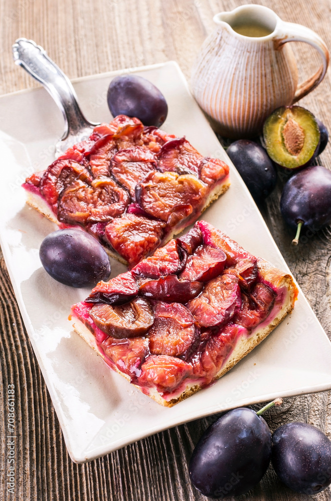 Traditional German plum cake with sliced plums served as close-up on a design plate