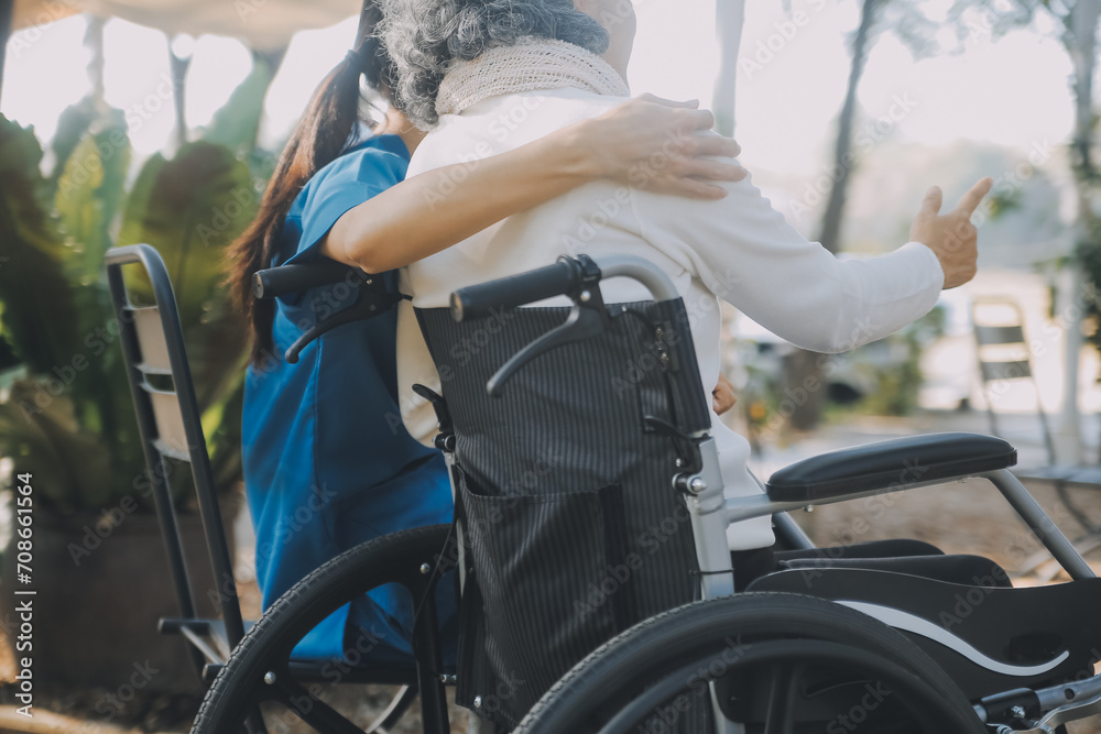 Obraz premium A nurse take care a senior male on wheelchair in his garden at home