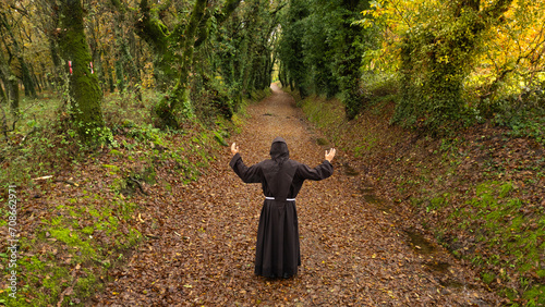 Fraile franciscano orando a Dios y haciendo el camino de Santiago en España en un hermoso paisaje rodeado de árboles y naturaleza al aire libre