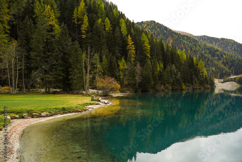 Panorama of green and yellow forest and Anterselva lake with blue calm water in Dolomites of Italy. Nature background. Beautiful wallpaper. Idyllic, harmonious atmosphere photo