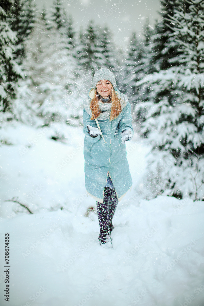 Girl play with snow in a snowy forest enjoying a winter day. Young traveler posing outdoors