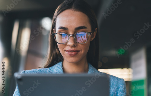 Smiling woman in suit and eyeglasses using tablet in office