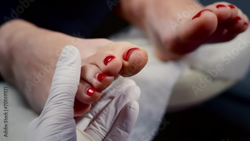 The manicurist examines the client's toenails. A nail art master does a pedicure on a girl's foot. A female client takes care of red nails in a beauty salon. Clean and healthy feet photo