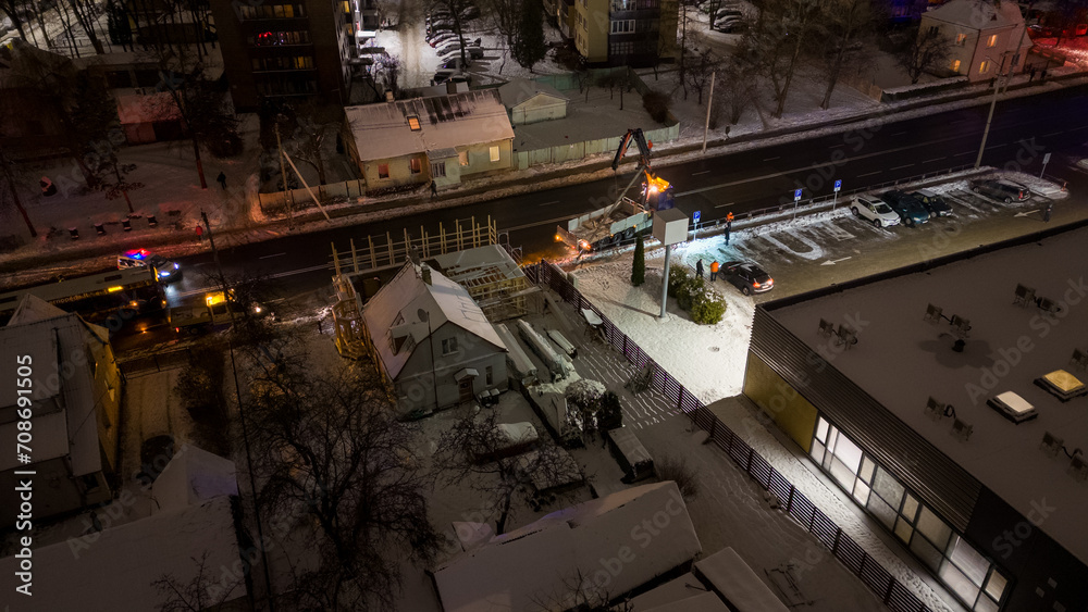 Drone photography of emergency service fixing broken electrical pole in a city during winter snowy night