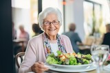 Happy elderly woman eating a salad
