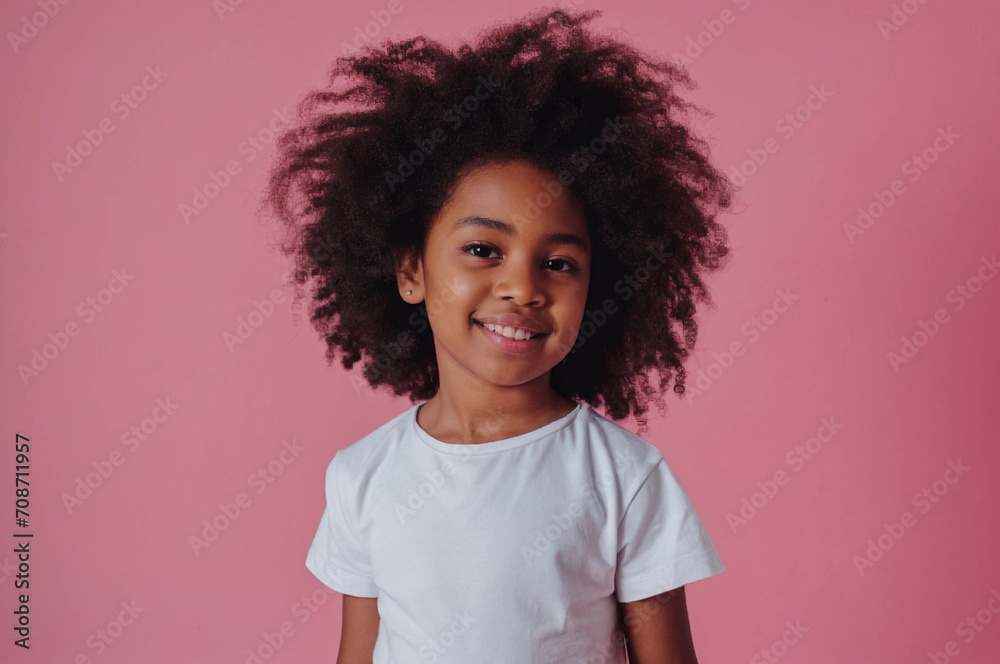 A little African American girl wearing white t-shirt for mockups. Child with natural hair, smiling on pastel pink background. A little African American girl wearing white t-shirt for mockups. Child with natural hair, smiling on pastel pink background.