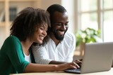 Dressed professionally, a couple shares smiles while engaged with a laptop screen, fostering a warm atmosphere in a home office, exchanging joyful information