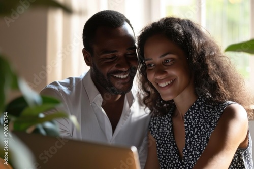 Amid a home office setting, a couple in business attire exchanges smiles, finding delight in the laptop screen's contents, fostering a positive atmosphere