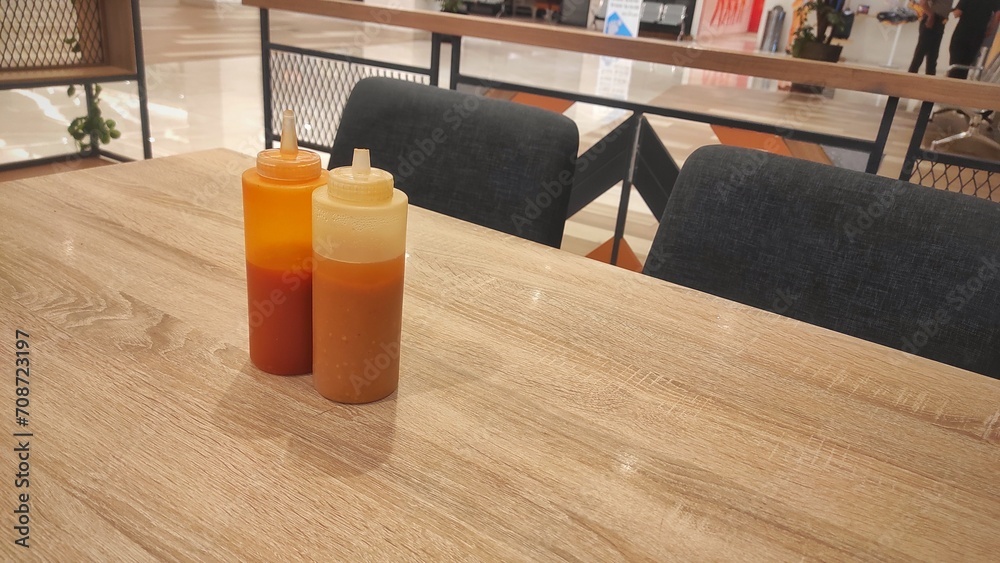 The bottle of Tomato sauce and chilli sauce on the wooden table of restaurant 