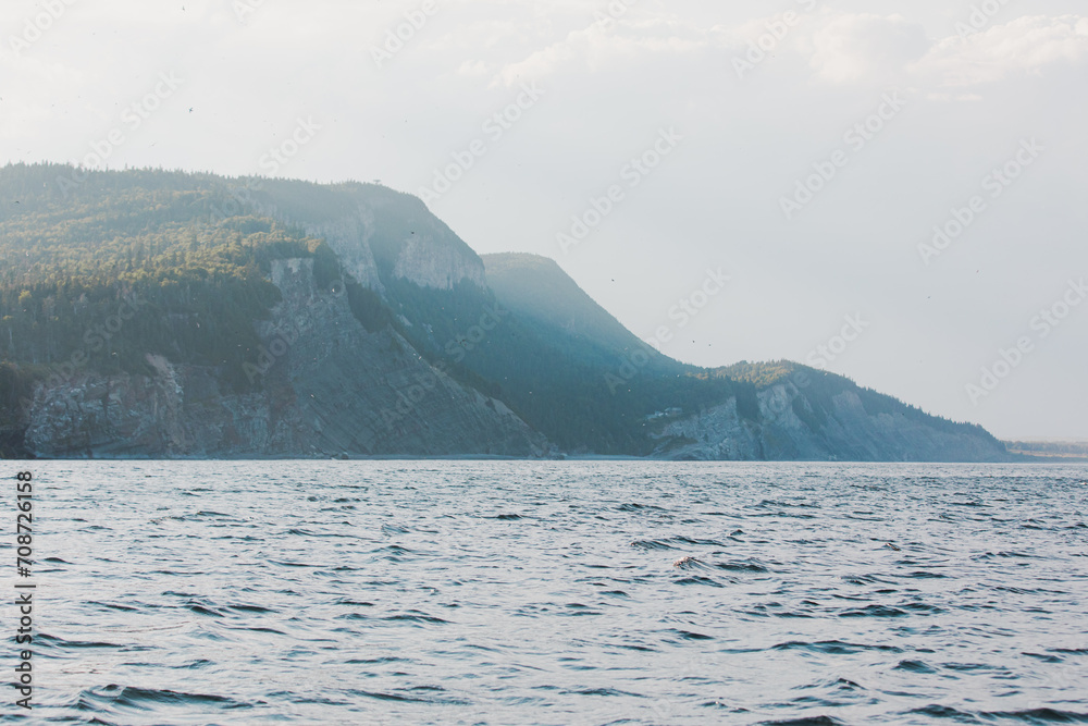 vue sur des falaises au loin en bord de mer lors d'une journée d'été ensoleillée avec une fine brume
