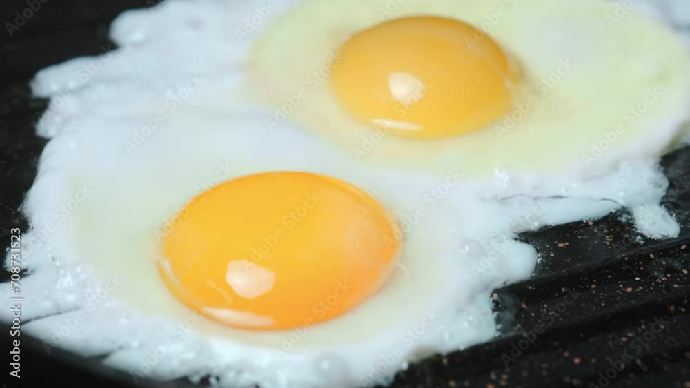 Chicken egg frying in a black frying pan close-up Chicken egg frying in a black frying pan close-up