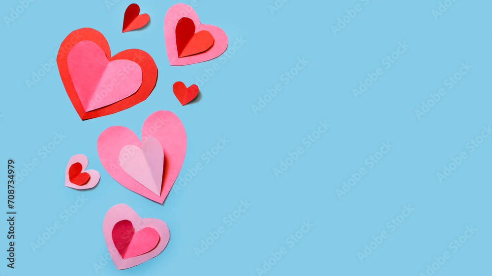 Banner with cute and delicate paper hearts arranged on a sky-blue background. Concept for Valentine's Day, Mother's Day, love, and friendship.
