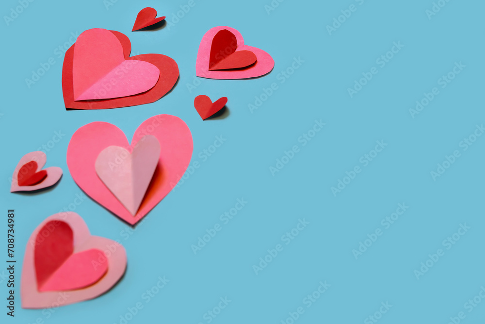 Banner with cute and delicate paper hearts arranged on a sky-blue background. Concept for Valentine's Day, Mother's Day, love, and friendship.