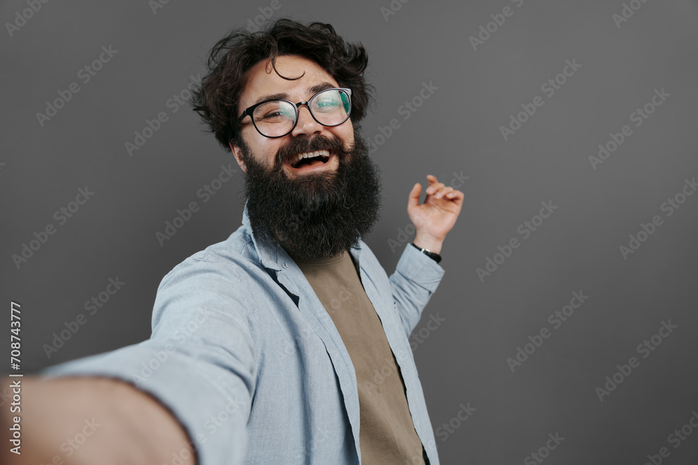 Obraz premium Delighted bearded man in casual wear taking a selfie, laughing and enjoying the moment, dark background