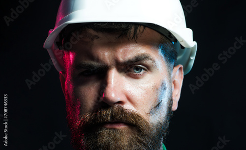 Closeup portrait of serious bearded architect  engineer or designer in protective hard hat. Industrial or mechanical worker in construction hardhat. Builder  foreman or repairman in safety helmet.