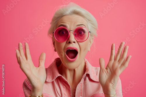 woman wearing business clothes and glasses looking fascinated with disbelief, surprise and amazed expression. Surprised Mature Woman with Glasses with Big Hair on an Pink Background photo