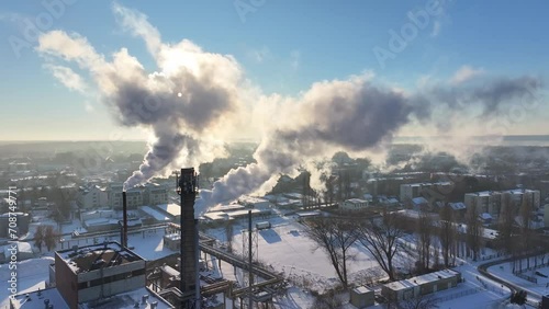 Winter scene captured by drone: Chimneys emit smoke, framing a snow-covered village. Tranquil and enchanting, ideal for showcasing winter's charm.