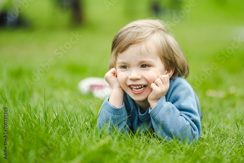 Cute toddler boy playing in blooming cherry tree garden on beautiful spring day. Adorable baby having fun outdoors.