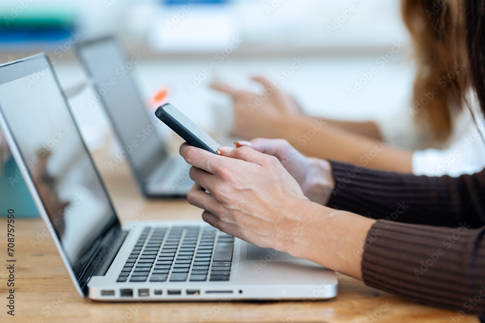 Beautiful businesswomen using their mobile phone while working with ...