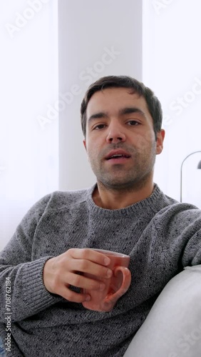 Hispanic man talking to camera sitting on sofa. Person giving advice.